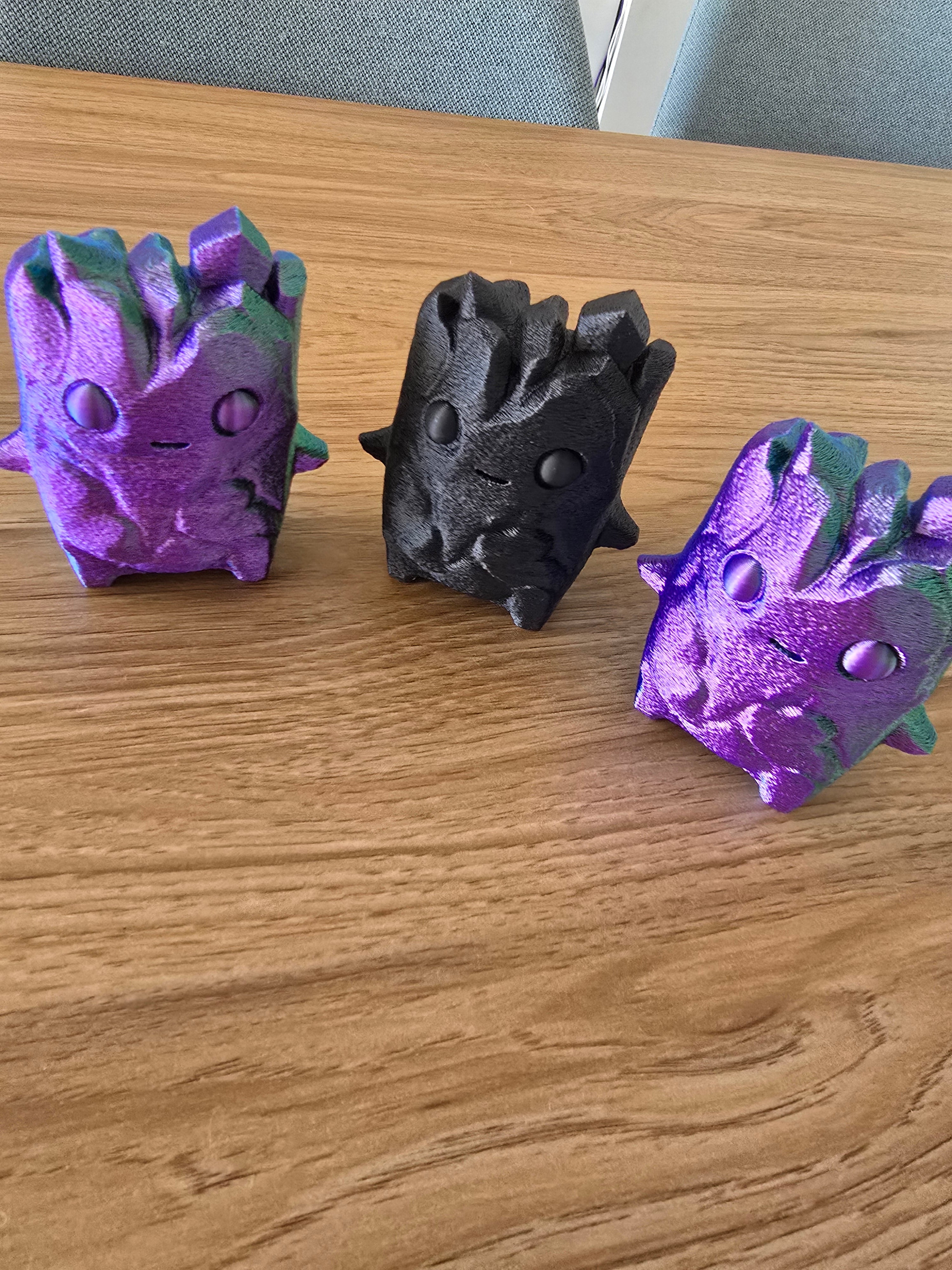 Three 3D printed Fortnite Sprite cube figures in purple, black and metallic purple
